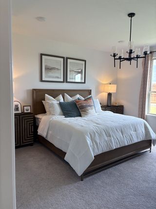 Model Home A cozy bedroom featuring a plush bed, elegant chandelier, and warm lighting, inviting relaxation.