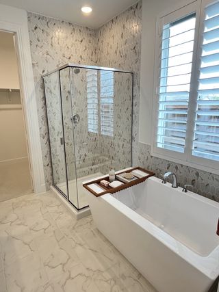 Model Home A modern bathroom featuring a glass shower, elegant hexagon tiles, and a luxurious soaking tub with natural light.
