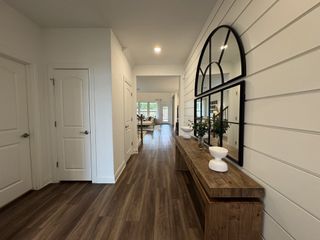 A hallway with wood floors, large mirrors, and elegant decor leading to a well-lit living area.