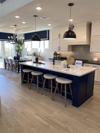 A modern kitchen with a navy island, sleek white cabinets, and elegant pendant lighting.