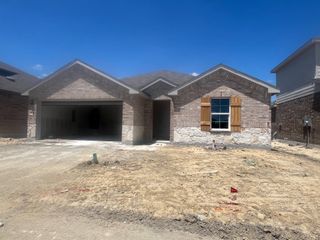 Street view A beautiful brick home with rustic shutters in Frontier Pointe by D.R. Horton, located in Princeton, TX.