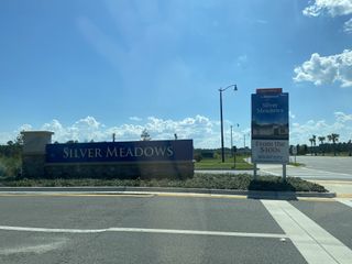 Street view Entrance to SilverLeaf: Silver Meadows 60s by Lennar in St. Augustine, FL, showcasing elegant signage under a clear blue sky.