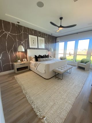 Model Home A stylish primary suite with floor-to-ceiling windows, elegant lighting, and a statement accent wall for a serene ambiance.