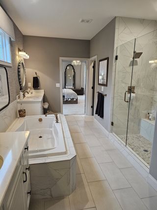 A spa-inspired bathroom with a soaking tub, a glass-enclosed shower, and gold fixtures, offering ultimate relaxation.