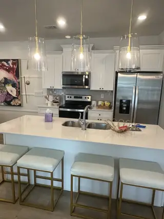 Modern kitchen with sleek white cabinets, stainless steel appliances, chic pendant lights, and an elegant island with seating.