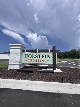 Street view Entrance sign for Holstein Crossing: Holstein Crossing 40s by Lennar in Asbury Lake, FL, under a vast, cloudy sky.