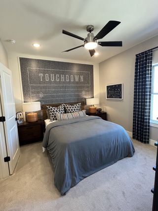 A stylish bedroom with a football theme, featuring a "TOUCHDOWN" mural, modern ceiling fan, and elegant bedding.