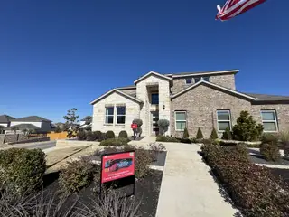 Street view A beautiful brick home with manicured landscaping in Stonewall Ranch 40s by Taylor Morrison (Liberty Hill, TX).