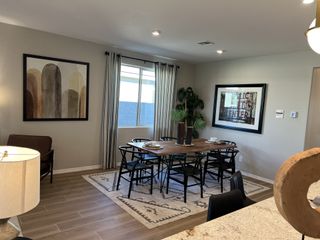 Model Home A cozy dining area featuring a round wood table, modern chairs, and tasteful artwork on neutral-toned walls.