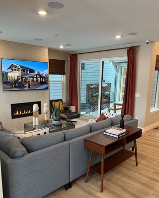 A cozy living room featuring a modern fireplace, sleek gray sofa, and large glass doors opening to an inviting patio.