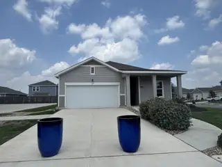 Street view A charming home with a porch and blue planters in Hymeadow by Starlight Homes, Maxwell, TX.