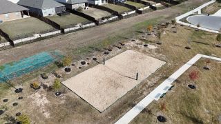Community Amenities A spacious sand volleyball court surrounded by newly planted trees in Riverview by Brightland Homes (Georgetown, TX).