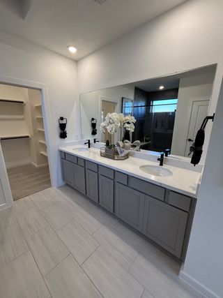 A modern bathroom with sleek grey cabinetry, dual sinks, and elegant tile flooring.