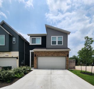 A beautifully designed townhome with a mix of brick and modern siding, a two-car garage, and a welcoming entrance in Village on Cooper Lane.