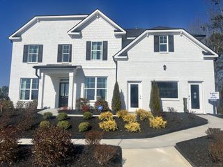 Street view A beautiful white brick home with black shutters and a landscaped yard in Water Oak Estates by D.R. Horton (Lawrenceville, GA).