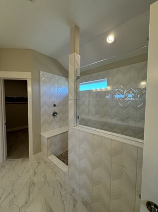A sleek bathroom with a chevron-tiled shower, bench seating, and a marble-patterned floor.