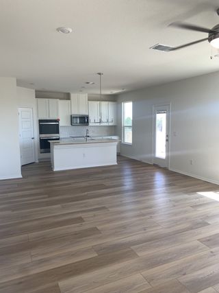 Model Home An open-concept kitchen and living area with white cabinetry and wood-look flooring.