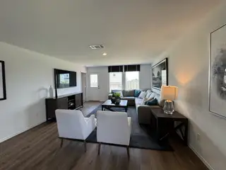 Model Home A cozy living room with wood floors, a plush sectional, and modern decor, bathed in natural light.