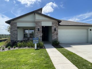 A modern stone-accented home with a manicured lawn in Phillips Landing by Starlight Homes (Groveland, FL).