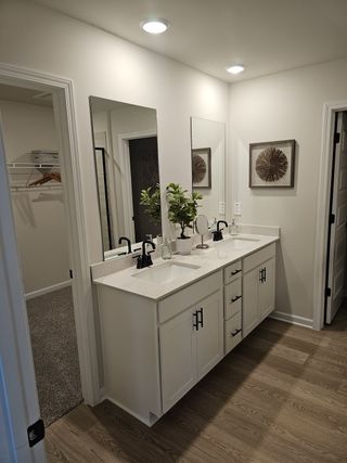 A modern bathroom with a dual-sink vanity, sleek fixtures, and elegant decor, featuring warm lighting and a wood floor.