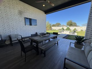 Chic outdoor patio with modern furniture, a TV, and lush garden views for relaxing and entertaining.