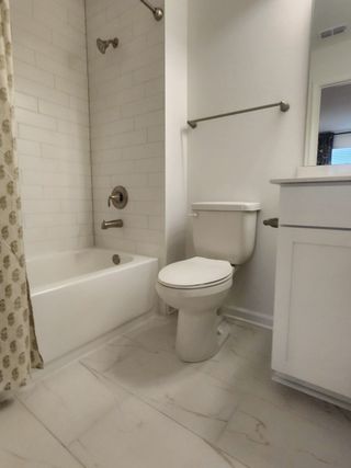 A cozy bathroom with a tiled shower-tub combo, sleek fixtures, and a modern white vanity.