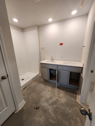 Model Home An unfinished bathroom with a shower area, vanity sink, and recessed lighting.