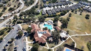 Community Amenities A luxurious community center in Travisso, featuring a sparkling pool, lush greenery, and walking trails (Leander, TX).