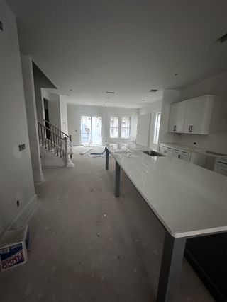 An expansive kitchen under construction with a large island, modern cabinets, and ample natural light.