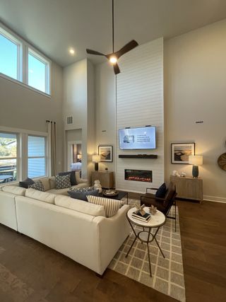 A spacious living room with high ceilings, cozy sectional, modern fireplace, and large windows enhancing natural light.