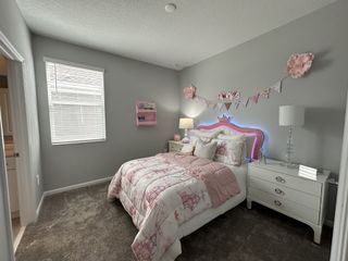 A cozy bedroom with a soft pink and gray theme, featuring decorative bunting, plush bedding, and stylish lighting.