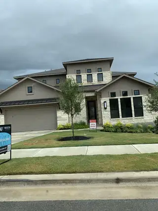 Street view A modern stone and stucco home with lush landscaping in Provence by Westin Homes (Austin, TX).