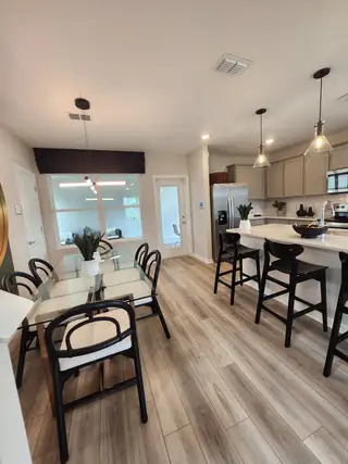 Model Home A modern kitchen-dining area with light wood flooring, sleek countertops, and stylish pendant lighting.