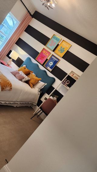 A vibrant bedroom with a bold striped accent wall, colorful decor, and a plush headboard, creating a fun and lively space.