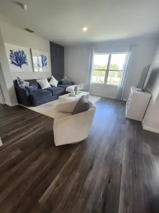 A cozy living room with a sleek navy sofa, abstract art, and rich wood flooring, offering a bright and inviting atmosphere.