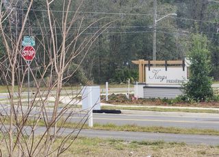 Entrance sign for Kings Preserve by Meritage Homes in Jacksonville, FL, nestled among lush greenery and a quiet street.