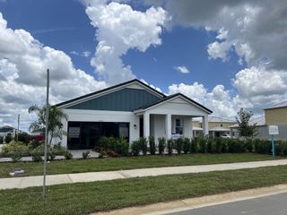 A modern white and blue home with lush landscaping in Mirada by Casa Fresca Homes (San Antonio, FL).