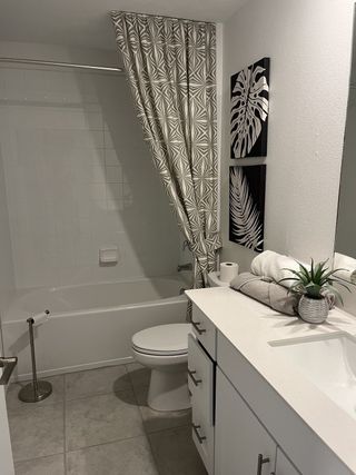 Model Home A modern bathroom with geometric shower curtain, white vanity, and tropical-themed decor.