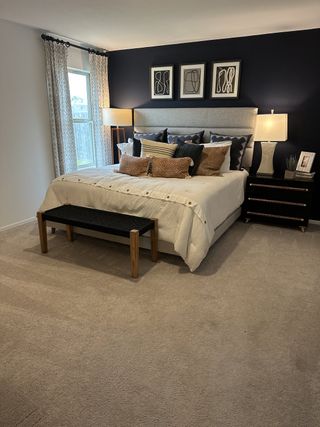 A cozy bedroom with a plush bed, navy accent wall, elegant lamps, and modern artwork.
