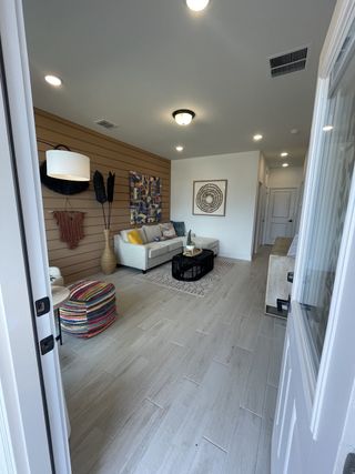 Model Home A modern living room with wood panel accents, cozy seating, vibrant decor, and tiled floors.