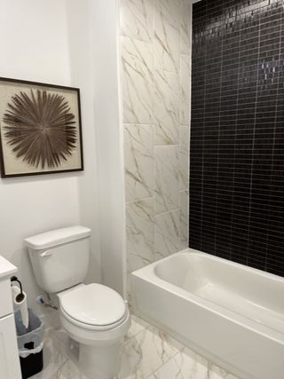 Model Home Elegant bathroom featuring a white bathtub, black accent wall, and marble tiles with modern decor.