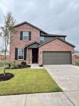 A charming red brick home with dark shutters and a tidy lawn in Ashford Crossing by Centex (Princeton, TX).