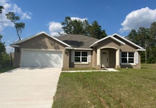 Street view A charming beige home with a spacious driveway and lush lawn in Marion Oaks by Zephyr Homes (Ocala, FL).