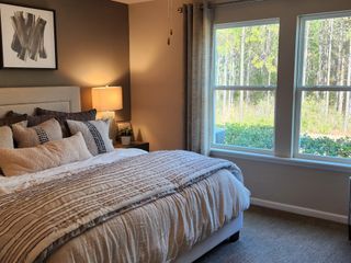 Model Home A sophisticated primary bedroom with a plush bed, large windows offering scenic views, and a relaxing atmosphere.