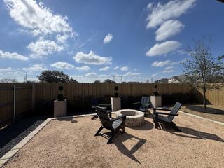 Model Home A cozy backyard fire pit area with modern black chairs under a clear blue sky. Perfect for outdoor gatherings.