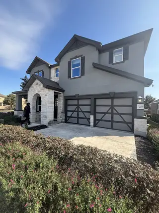 Street view A modern gray and stone facade home with stylish shutters in Hidden Canyons at TRP by KB Home (San Antonio, TX).