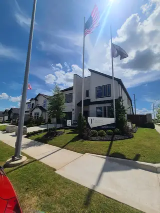 Street view Modern model home with sleek design and flags, situated in the Madero community by Trophy Signature Homes (Haslet, TX).