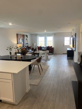 An open-plan living room with modern décor, bright windows, and cozy seating on a sleek wood floor.