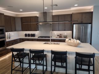 A modern kitchen featuring wooden cabinetry, sleek appliances, and a spacious island with bar seating.
