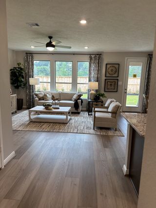 Model Home An inviting living room with light wood floors, cozy seating, and large windows offering scenic views.